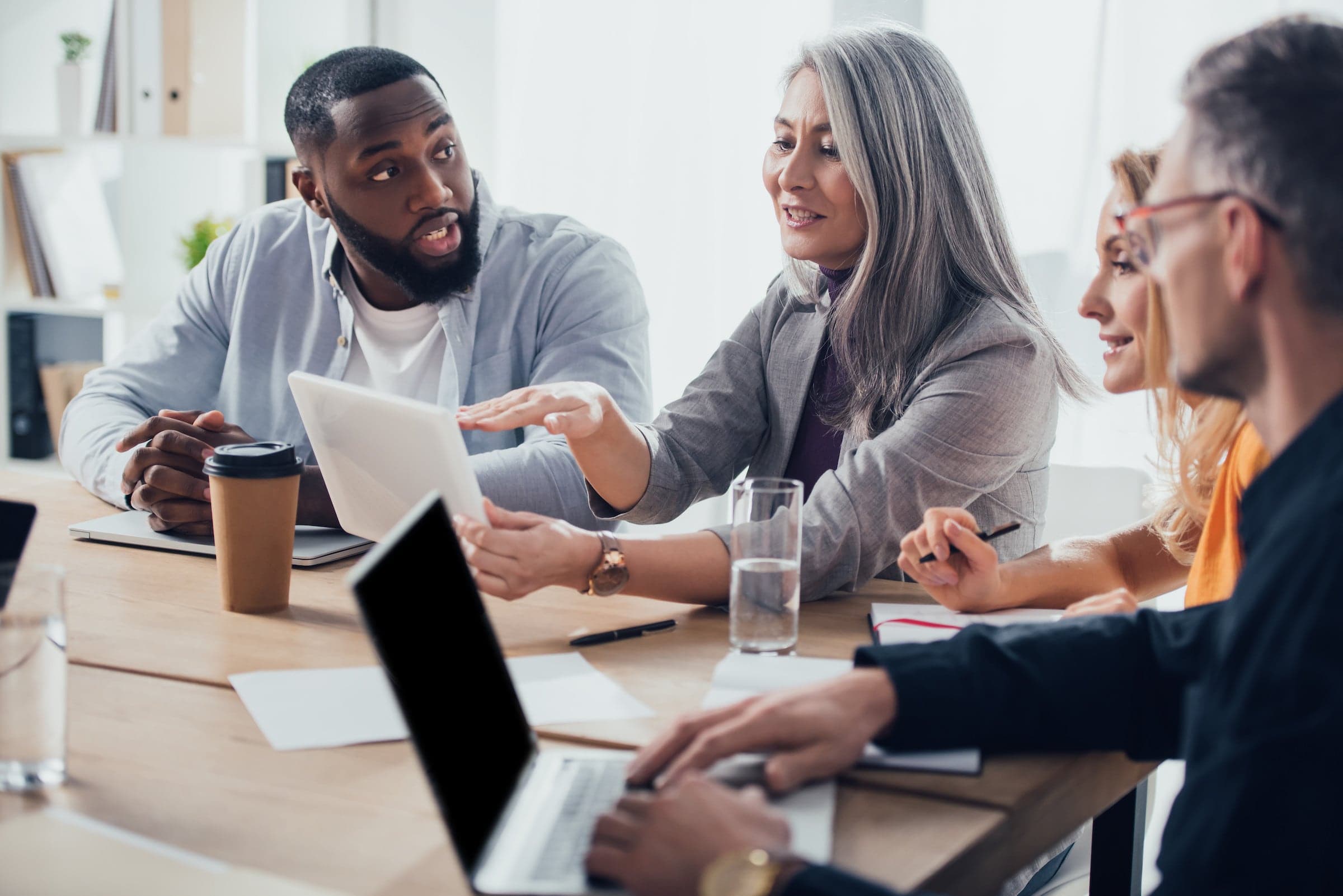 A person presenting information on their tablet to three other colleagues.