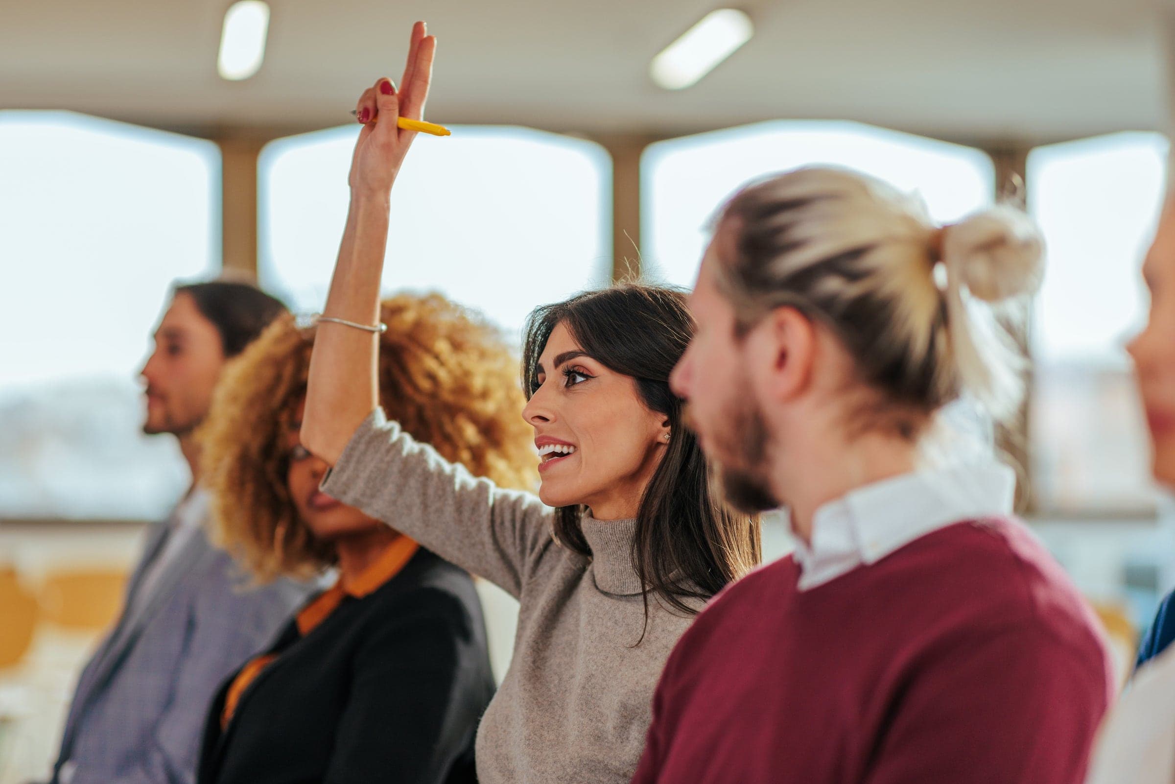 A person in a row of other people raising their hand during a presentation.